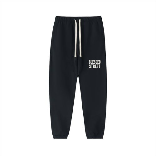 Black jogger sweatpants with a white drawstring and 'BLESSED STREET' printed in white on the left thigh, shown against a plain white background.