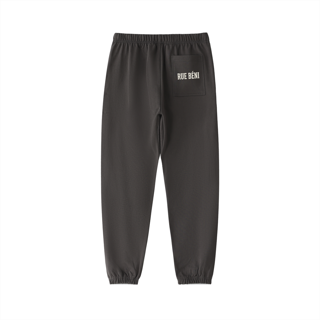 Dark gray jogger pants with gold embroidered graphics, including a peace sign with 'PEACE' and 'WOW' on the lower legs, and a gold crest on the upper thigh pocket, shown against a plain white background.