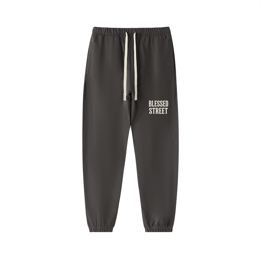 Dark gray jogger pants with a white drawstring and 'BLESSED STREET' printed in white on the left thigh, shown against a plain white background.
